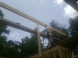 Carpenter setting a ridge beam over a new addition frame — Ice Dam Removal by Roofing Brothers in Kamrar