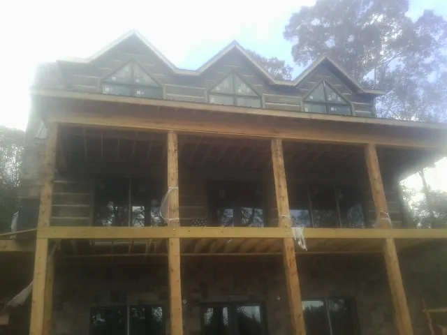 Dormers and porch framing on a large log home under construction — Roof Coating work by our crew in Kamrar