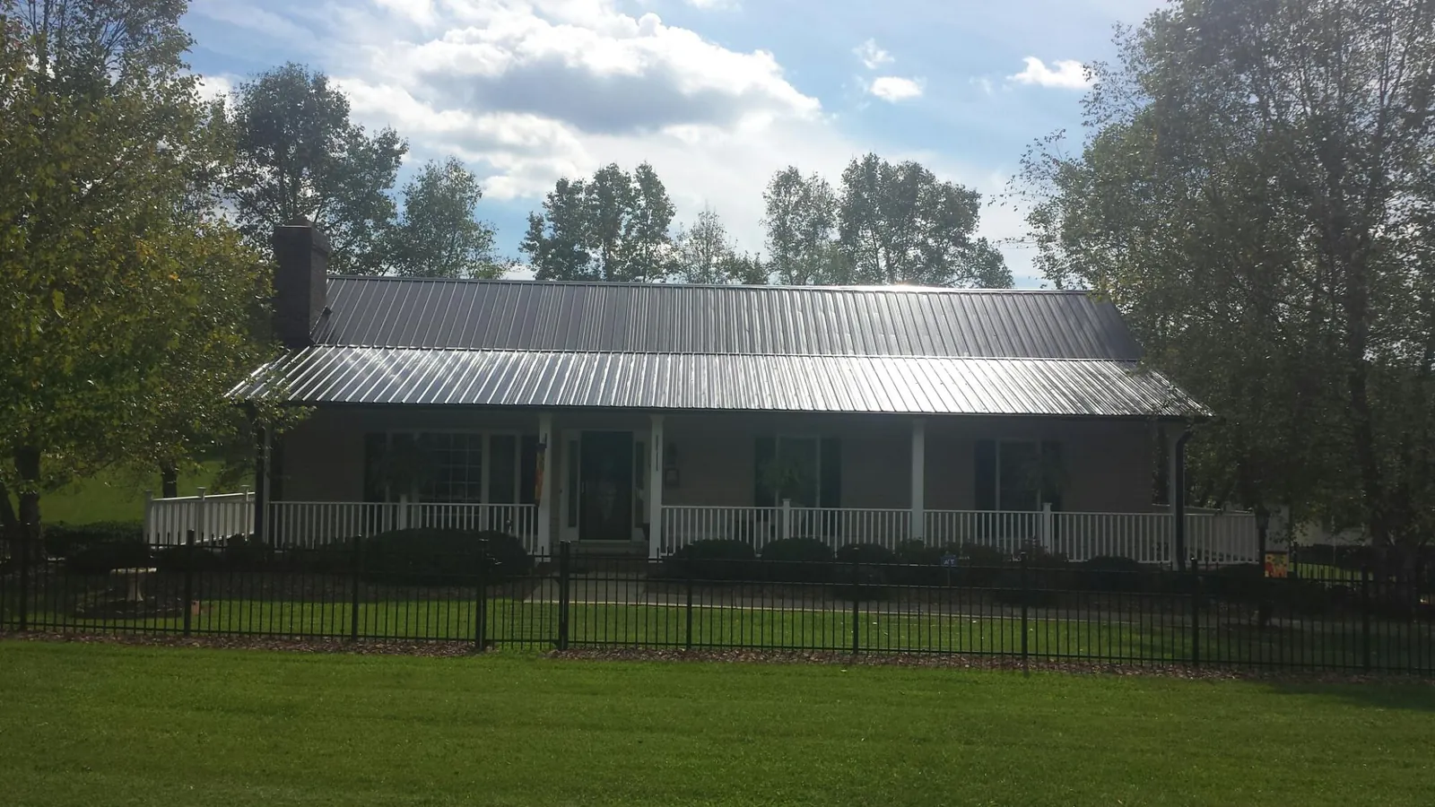 Gray metal roof on a brick ranch with a full width front porch — Gutter Guard Installation work by our crew in Kamrar