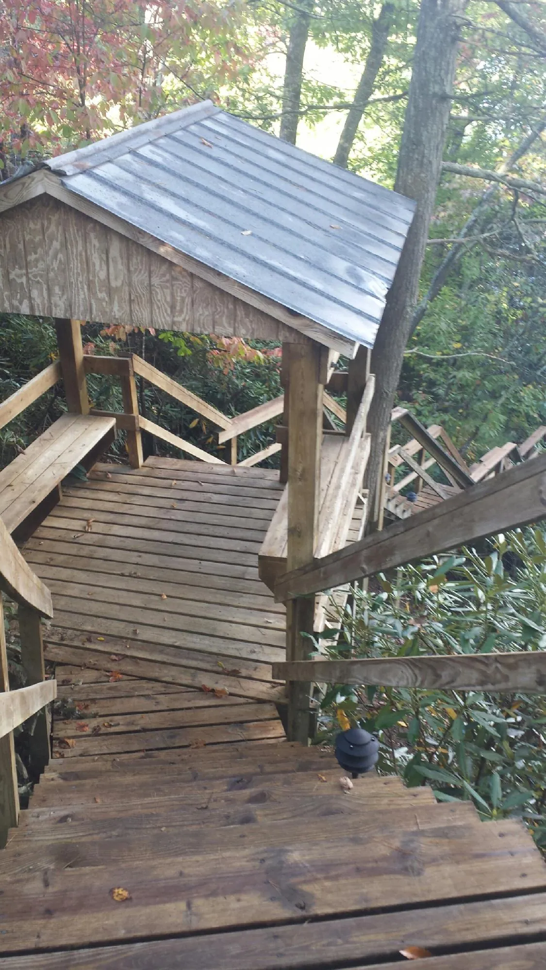 Metal roofed shelter over wooden steps on a wooded walkway — Skylight Repair & Installation work by our crew in Kamrar