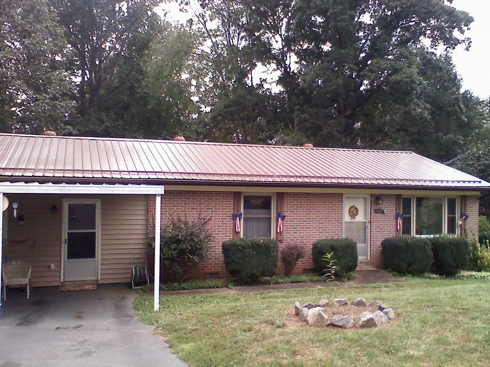 Bronze metal roof and carport on a brick ranch home — Roof Repair work by our crew in Kamrar