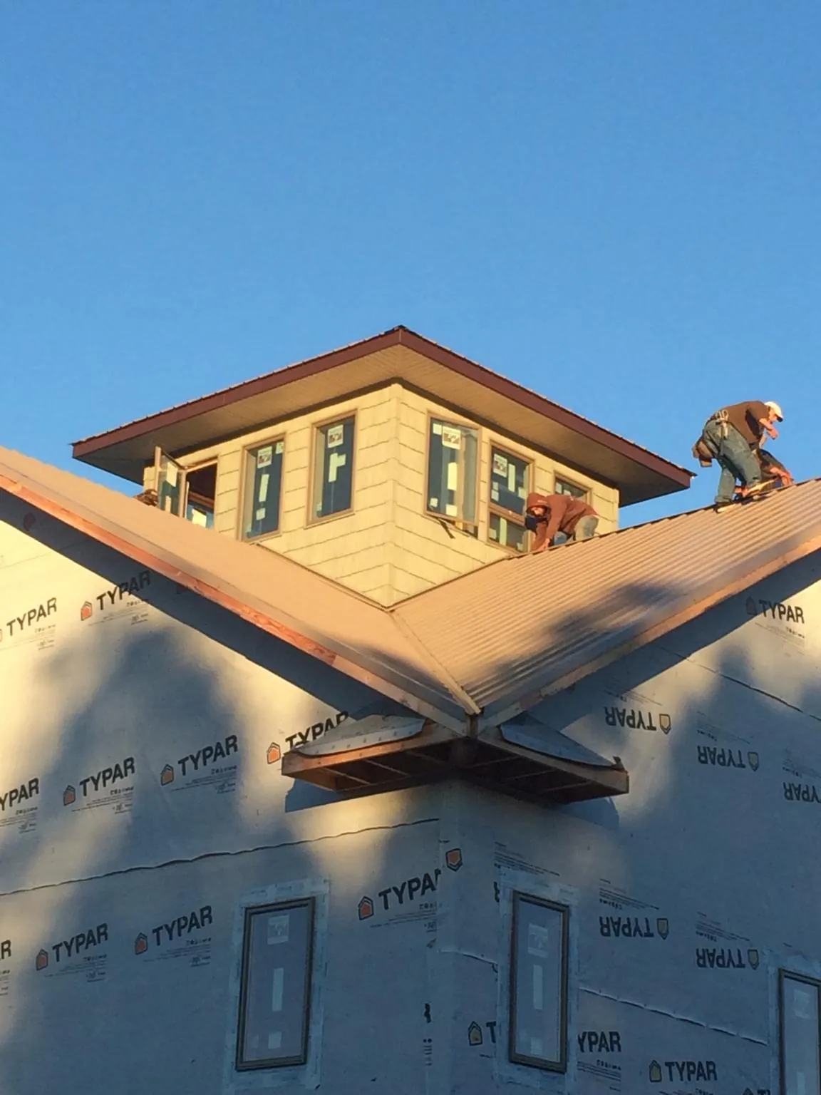 Roofers working around a rooftop cupola on a new metal roof at sunset — Roof Waterproofing in Kamrar by Roofing Brothers